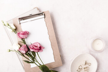 Blank paper clipboard, bouquet flowers, candle and office accessories. Flat lay, top view, copy...