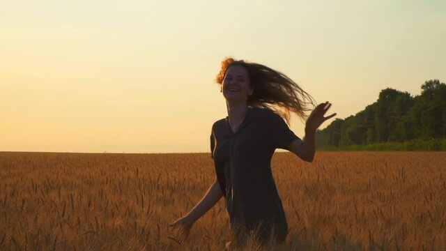 woman run away in sunny horizon field in evening at sunset. Young Caucasian girl have fun outdoors in summer. Sunny day rays. from back go away from camera. Without face. Place for text. Freedom