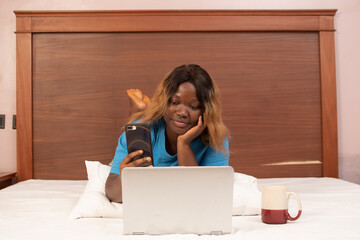 young african woman using her phone and laptop simultaneously