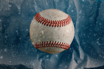 Old baseball ball for winter season with snow on blue background.