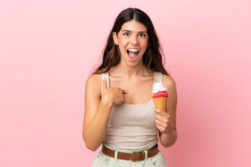 Young caucasian woman with a cornet ice cream isolated on pink background with surprise facial expression