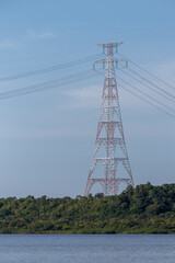 Big electricity tower built on the banks of a river, with blue sky in the background