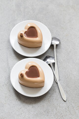 Coffee cream dessert, Panna Cotta in the shape of a heart on a plate on a light gray background top view