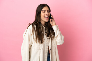 Young caucasian woman isolated on pink background keeping a conversation with the mobile phone