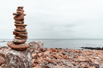 Fototapeta na wymiar Balancing stones on the rocky coast of Hovs Hallar nature reserve in Sweden. Blurred background. Selective focus.