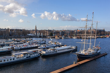 Scenic Amsterdam harbor with boats, ships and traditional sailing barque on the panoramic city view background, Netherlands