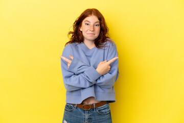 Teenager reddish woman isolated on yellow background pointing to the laterals having doubts