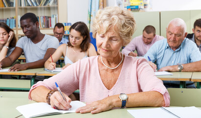 Fototapeta premium Mature woman take a written exam in the classroom