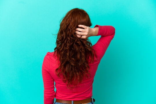 Teenager reddish woman isolated on blue background in back position and thinking