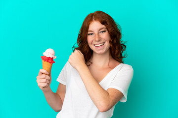 Teenager reddish woman with a cornet ice cream isolated on blue background celebrating a victory