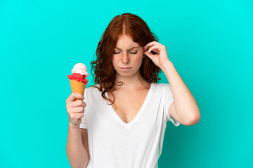 Teenager reddish woman with a cornet ice cream isolated on blue background frustrated and covering ears