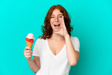 Teenager reddish woman with a cornet ice cream isolated on blue background shouting with mouth wide open