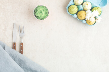Elegant easter spring table design with cutlery, tablecloth, succulente, easter eggs in blue colors on beige table. Background with toned mockup. Top view, flat lay