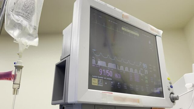 Patient Vitals on screen , IV fluids drip in operating room
