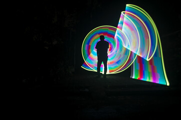 	
One person standing alone against a Colourful circle light painting as the backdrop	

