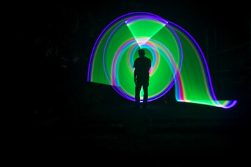 	
One person standing alone against a Colourful circle light painting as the backdrop	
