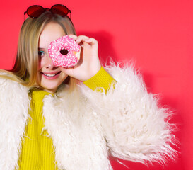 little cute blond teenage girl posing in fashion style with donut on red background, lifestyle people concept