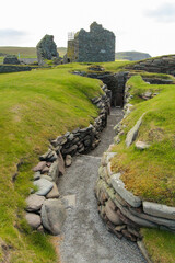 Deep pathway surrounded with stone walls covered by green grass leading to the Laird's House at the...
