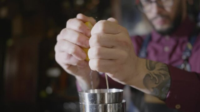 A bartender squeezing lemons in the shaker