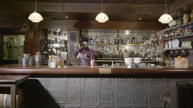 A bartender prepares his drink by mixing the ingredients
