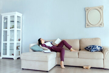 an adult female student is tired of studying from books and lay down on the sofa. second education, re-qualification