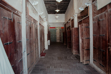 A corridor full of shops with old wooden doors with metal hinges inside Souq Waqif in Qatar