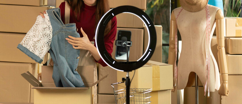 beauty female fashion vlogger presenting blue dress to camera and smiling showing clothes selling online live streaming.Business online e-commerce at home.