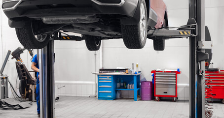Automobil on lift for wheel suspension maintenance. Car service garage