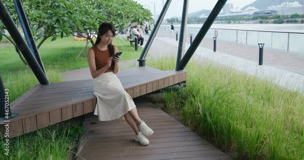 Poster woman use smart phone and sit at park