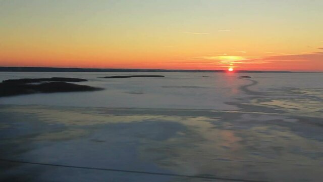 View from the window on the high-speed train Sapsan huge frozen lake at sunset. In shot there is also a home (POV)
