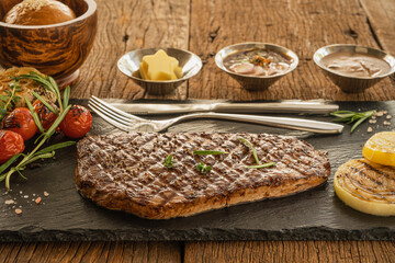 beef shoulder steak on stone plate with sauce and bread and butter