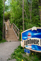 A wooden staircase leads up a hill through a forest at the bottom of the Lighthouse Trail in...