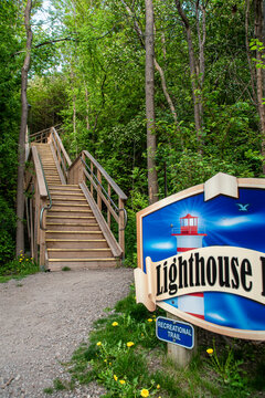 A wooden staircase leads up a hill through a forest at the bottom of the Lighthouse Trail in Goderich, Ontario, leading to the town's historic lighthouse.