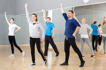Group of adult people warming up before dance training in fitness center