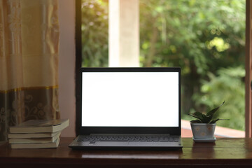 Close-up view of open blank screen laptop computer on wood table.