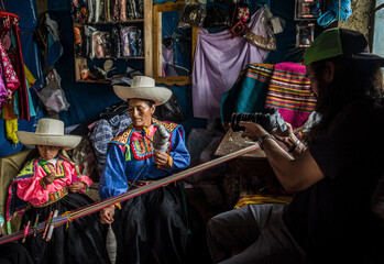 Fotógrafo  realiza fotografías con Una  madre latinoamericana andina que enseña el telar de...