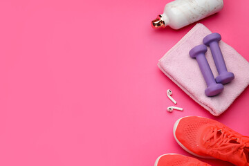 Dumbbells, shoes and earphones on pink background