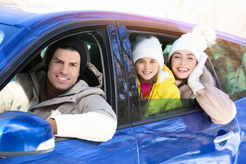 Happy family sitting in car on winter day