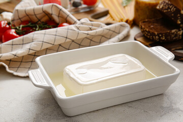 Baking dish with feta cheese on light background