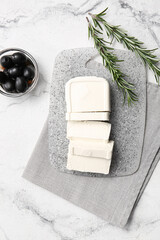 Board with feta cheese, olives and rosemary on light background