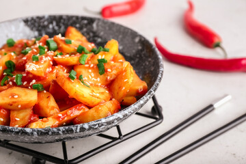 Plate with honey chilli potato and chopsticks on light background