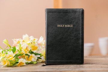 Black Holy Bible with flowers on table in room