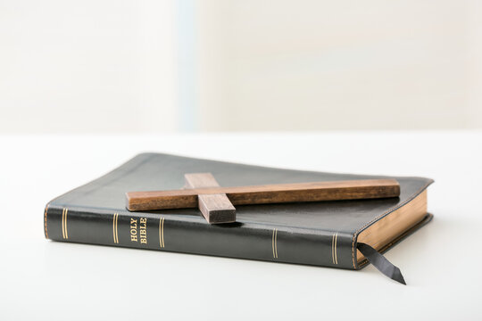 Black Holy Bible with wooden cross on table