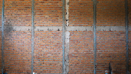Red brick wall and PVC pipe. A bare brick wall background with blue plumbing inserted in the natural light side view of a building under construction with copy space. Selective focus
