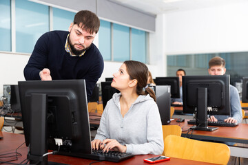 Male trainer helping young female student in computer class. High quality photo