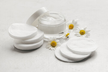 Fototapeta na wymiar Clean cotton pads, face cream and Chamomile flowers on light background, closeup