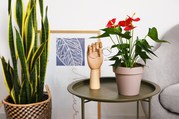 Wooden hand holding eyeglasses and Anthurium flower in pot on table