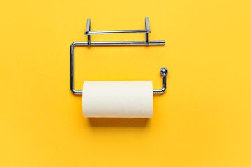 Holder with cardboard tube for toilet paper on orange background