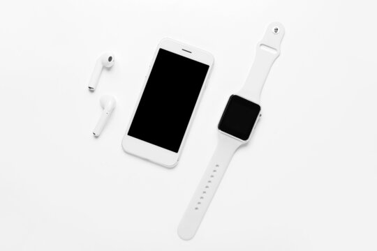 Modern Earphones, Mobile Phone And Smart Watch On White Background