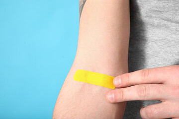 Man with medical patch on his arm against color background, closeup